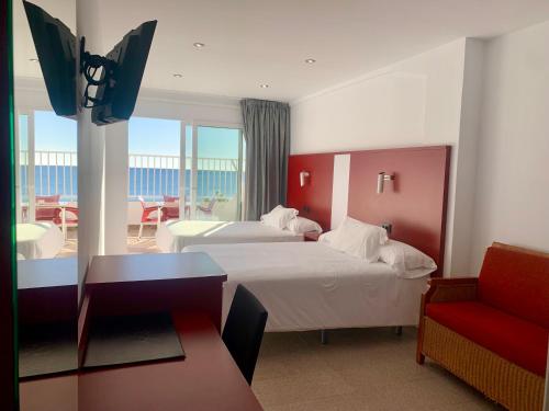 a hotel room with two beds and a red chair at Hospedium Hotel Continental in Mojácar