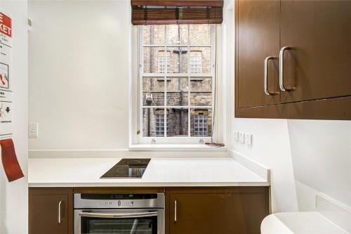 a kitchen with a stove top oven next to a window at Stay Mayfair in London