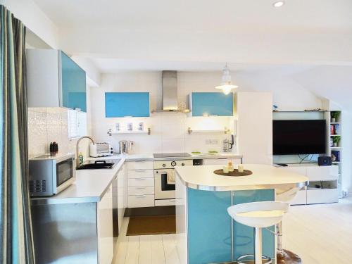 uma cozinha com armários azuis e brancos e uma mesa em The Mermaid Loft - Trebarwith Strand Cornwall em Tintagel