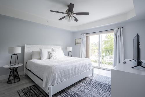 a white bedroom with a bed and a ceiling fan at Modern 1BR condo-5 min Bike ride to the beach in Naples