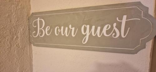 a sign that says be our guest on a wall at Mains Street Retreat in Lockerbie