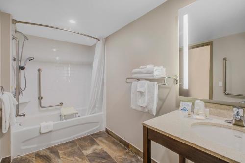 a bathroom with a tub and a sink and a shower at Days Inn & Suites by Wyndham Lindsay in Lindsay
