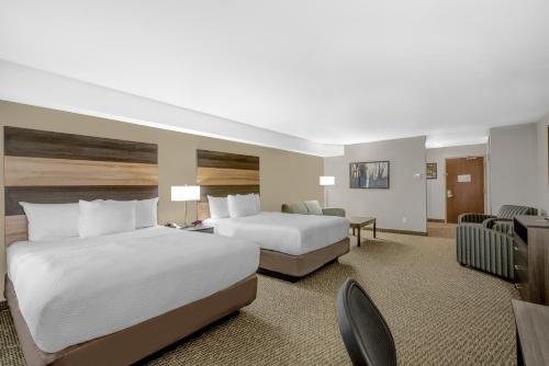 a hotel room with two beds and a desk at Days Inn & Suites by Wyndham Lindsay in Lindsay