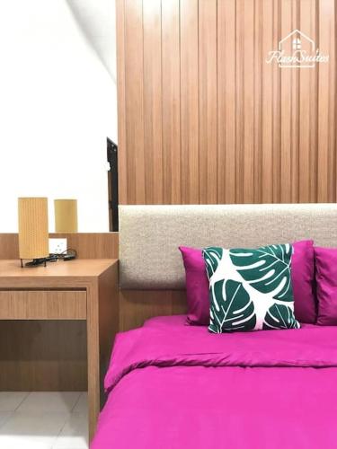 een slaapkamer met een bed met roze lakens en een bureau bij Melaka Klebang Bungalow by HelloSuites in Melaka