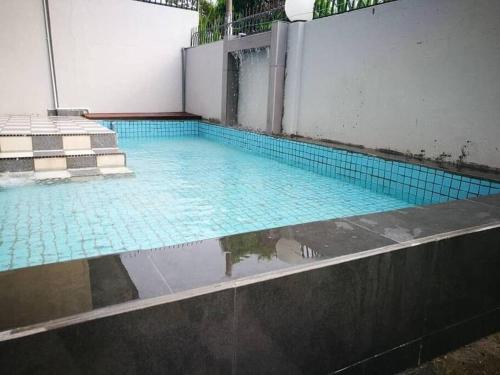 een zwembad met blauwe tegels in een gebouw bij Melaka Klebang Bungalow by HelloSuites in Melaka
