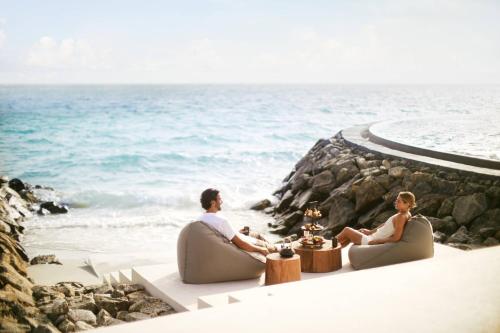 a man and a woman sitting on the beach at The Ritz-Carlton Maldives, Fari Islands in North Male Atoll