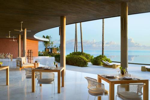 a restaurant with tables and chairs and a view of the ocean at The Ritz-Carlton Maldives, Fari Islands in North Male Atoll