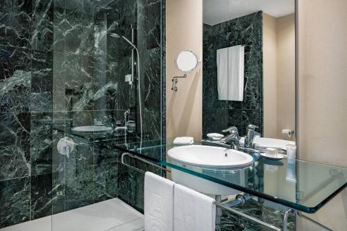 a bathroom with a sink and a glass shower at AC Hotel Málaga Palacio by Marriott in Málaga