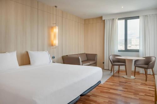 una camera d'albergo con letto, tavolo e sedie di AC Hotel Málaga Palacio by Marriott a Málaga