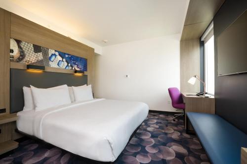 a white bed in a room with a desk and a chair at Aloft Austin Airport in Austin