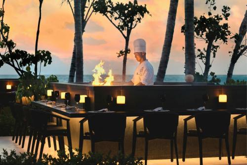 a chef standing in front of a table with a grill at The Ritz-Carlton Maldives, Fari Islands in North Male Atoll