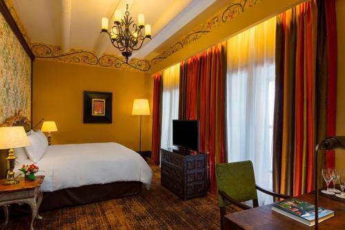 a bedroom with a bed and a television and a table at Palacio del Inka, a Luxury Collection Hotel by Marriott in Cusco