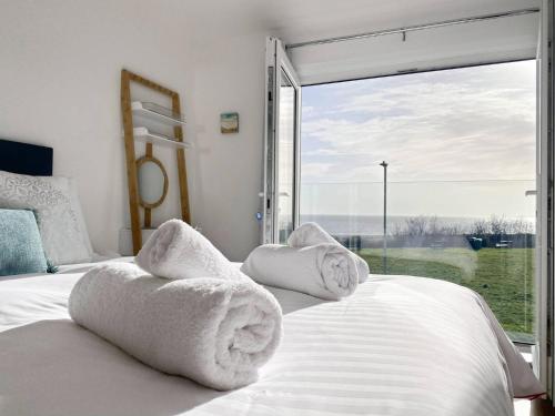 a bedroom with white towels on a bed with a large window at 4 Sea View Walk, Pakefield in Pakefield