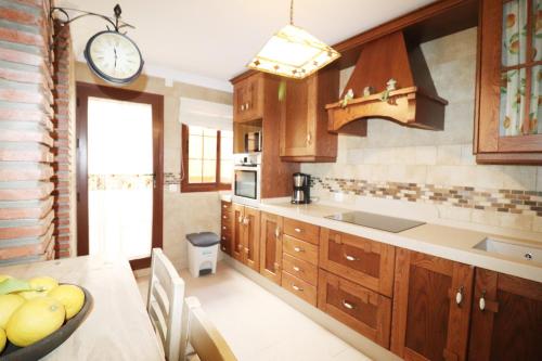 a kitchen with wooden cabinets and a clock on the wall at Casa Nayroa by Spainsunrentals 1019 in Nerja