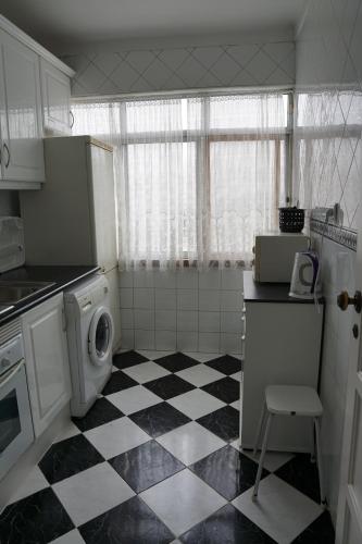a kitchen with a black and white checkered floor at Herois Apartment in Damaia