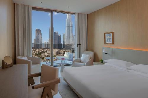 sypialnia z łóżkiem i krzesłami oraz dużym oknem w obiekcie The Dubai EDITION w Dubaju