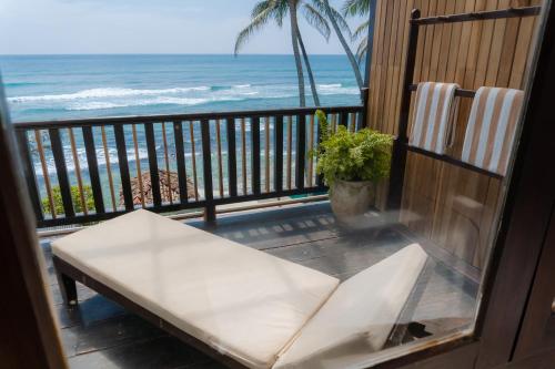 a balcony with a white bench and the ocean at Surf Station in Ahangama