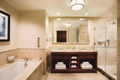 a bathroom with a tub and a sink and a mirror at The Ritz-Carlton, Aruba in Palm-Eagle Beach
