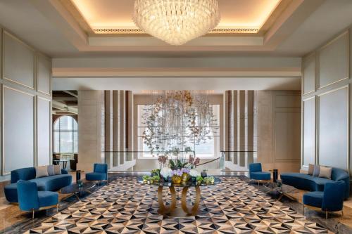 a lobby with blue chairs and a chandelier at The St. Regis Marsa Arabia Island, The Pearl Qatar in Doha