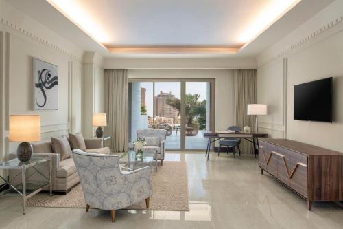 a living room with a couch and a tv at The St. Regis Marsa Arabia Island, The Pearl Qatar in Doha