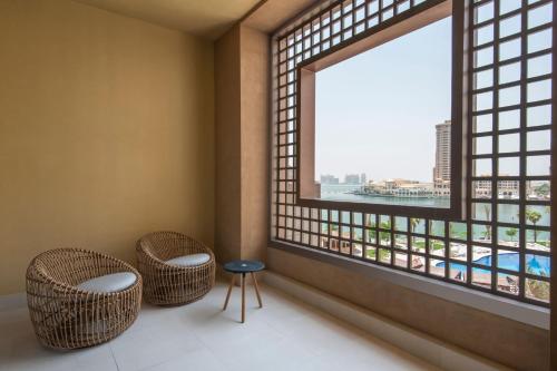 a room with two chairs and a large window at The St. Regis Marsa Arabia Island, The Pearl Qatar in Doha