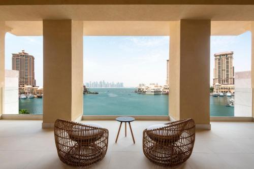 two chairs and a table in a room with a view of the water at The St. Regis Marsa Arabia Island, The Pearl Qatar in Doha