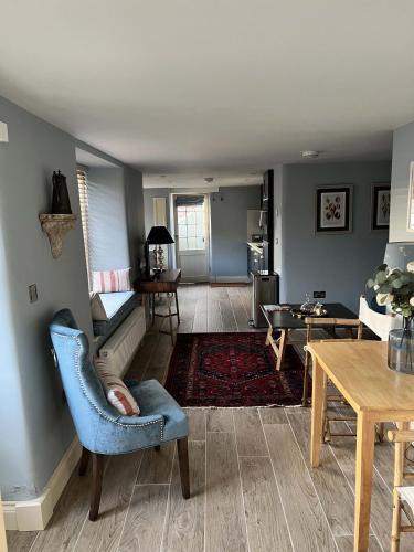 a living room with a blue chair and a table at Sandpiper in Fowey