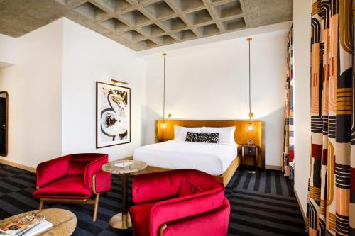 um quarto de hotel com uma cama e duas cadeiras vermelhas em Hotel Indy, Indianapolis, a Tribute Portfolio Hotel em Indianápolis