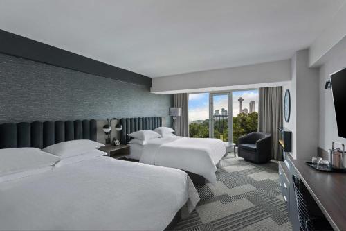 a hotel room with three beds and a large window at Sheraton Fallsview Hotel in Niagara Falls