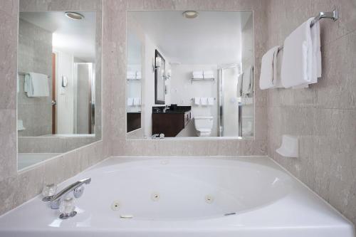 a bathroom with a large white tub with a large mirror at Sheraton Fallsview Hotel in Niagara Falls