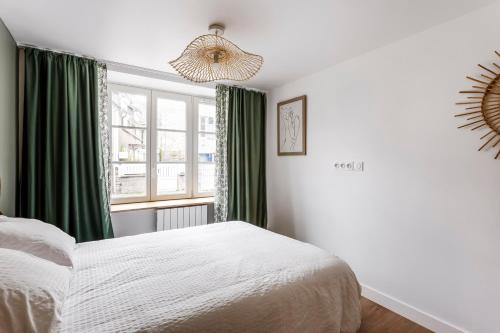 een slaapkamer met een bed en een raam met groene gordijnen bij Le 37 - Maison 2 chambres en bord de mer in Saint-Cast-le-Guildo