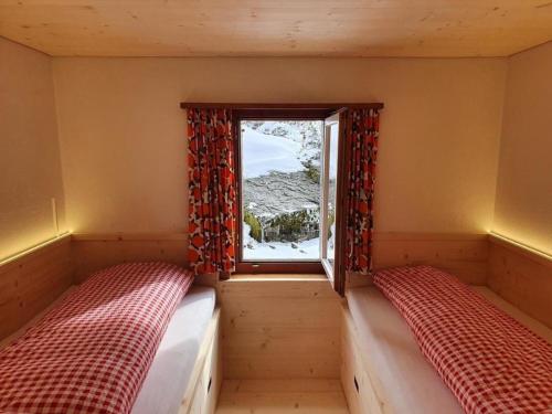 um pequeno quarto com 2 camas e uma janela em Ferienhaus Oberguet em Unterwasser