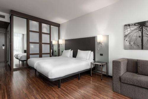 um quarto com uma grande cama branca e um sofá em AC Hotel La Finca by Marriott em Pozuelo de Alarcón