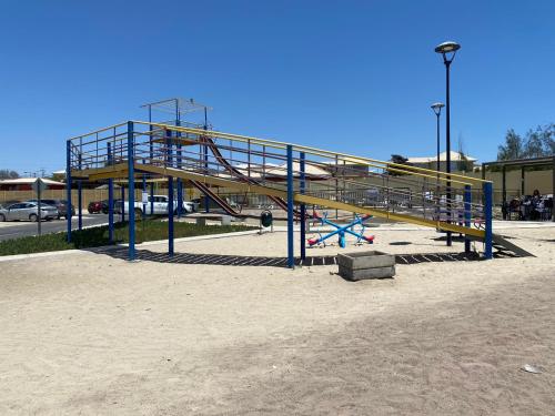 un parque infantil con tobogán en un aparcamiento en Departamentos Caldera Suites, en Caldera