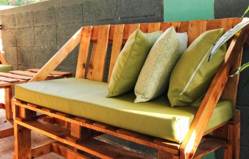 a wooden chair with green pillows on a porch at Casa Isabel in Rincon