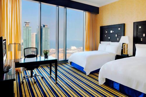 a hotel room with two beds and a desk and a window at Marriott Marquis City Center Doha Hotel in Doha