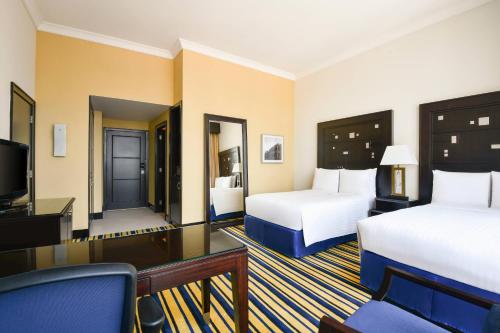 a hotel room with two beds and a television at Marriott Marquis City Center Doha Hotel in Doha