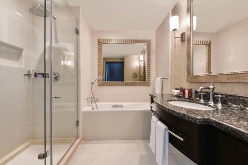 a bathroom with a tub and a sink and a shower at Marriott Marquis City Center Doha Hotel in Doha