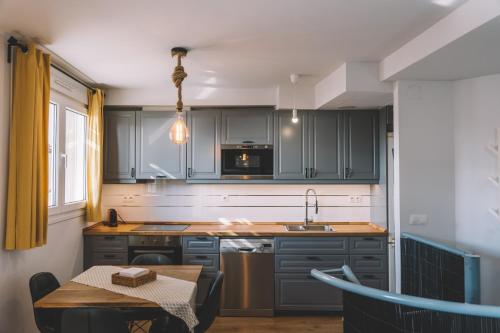 eine Küche mit grauen Schränken und einem Tisch und einem Tableablish in der Unterkunft Duplex Victoria Beach Málaga in La Cala del Moral