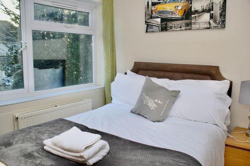 a bed with white sheets and pillows next to a window at Contractor's Haven- 4-Bedroom House with Free Parking, Super Fast WiFi, Fran Properties in Aylesbury, Pets are Welcome! in Buckinghamshire