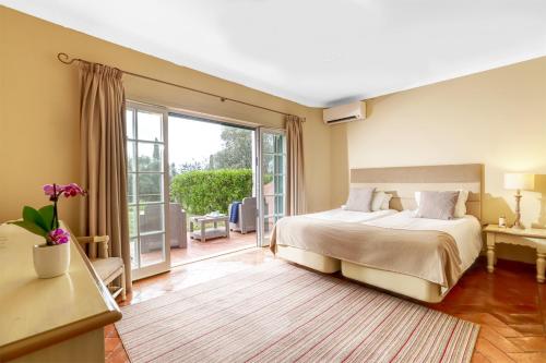 um quarto com uma cama e uma porta de vidro deslizante em Cegonha Country Club em Vilamoura