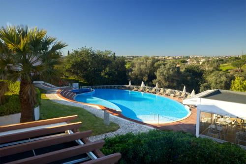 a swimming pool in a resort with a palm tree at Cegonha Country Club in Vilamoura