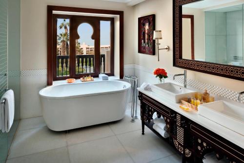 a bathroom with a tub and two sinks and a mirror at Marriott Mena House, Cairo in Cairo
