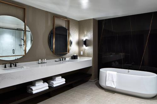 a bathroom with a large tub and a large mirror at UNC Charlotte Marriott Hotel & Conference Center in Charlotte