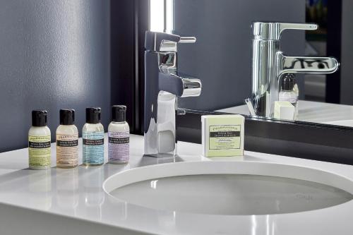 a bathroom sink with three bottles ofodorizers and a mirror at Aloft Chattanooga Hamilton Place in Chattanooga