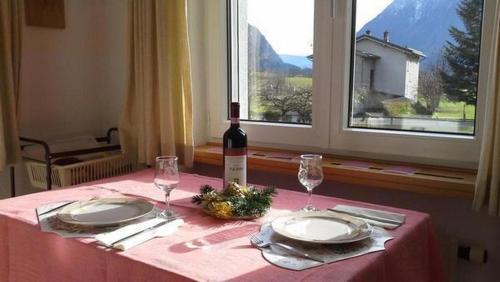 una mesa con una botella de vino y dos copas en Schöne, sonnige 25-Zimmer Parterre-Ferienwohnung, en Poschiavo