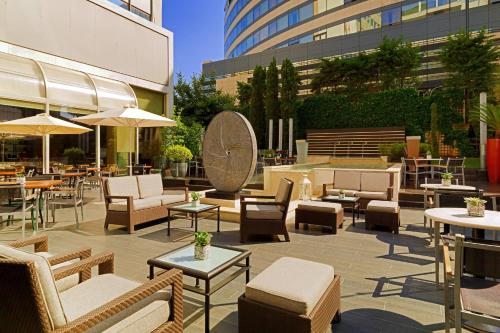 a patio with chairs and tables and tables and buildings at Athens Marriott Hotel in Athens