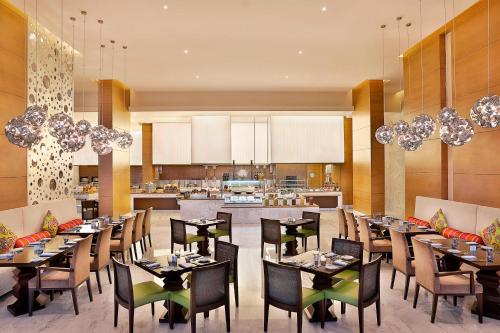 a restaurant with tables and chairs and a kitchen at Marriott Hotel Al Forsan, Abu Dhabi in Abu Dhabi