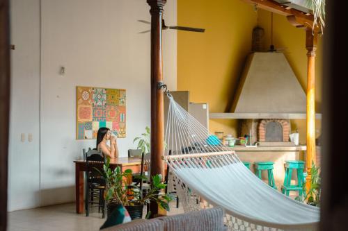 a hammock in a room with a woman sitting at a table at Miskitu casa boutique in Granada