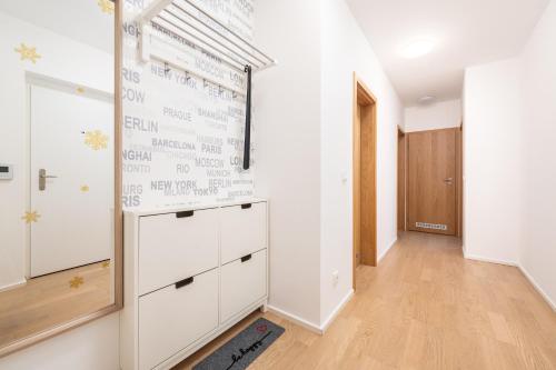 un pasillo con paredes blancas y una gran pared con armarios blancos. en Mill Apartments, en Brno